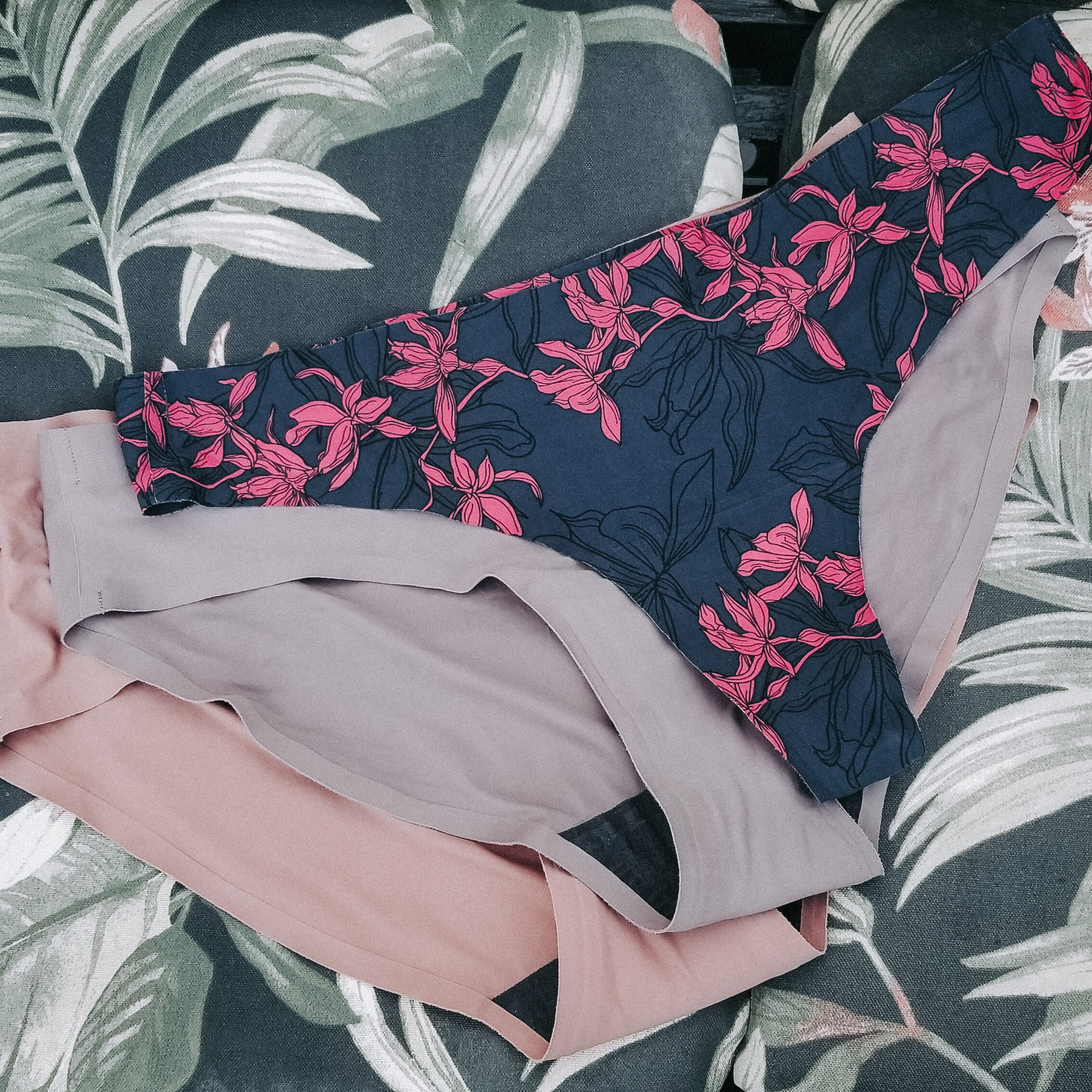 Three pairs of women's underwear laid out flat on a tropical background.